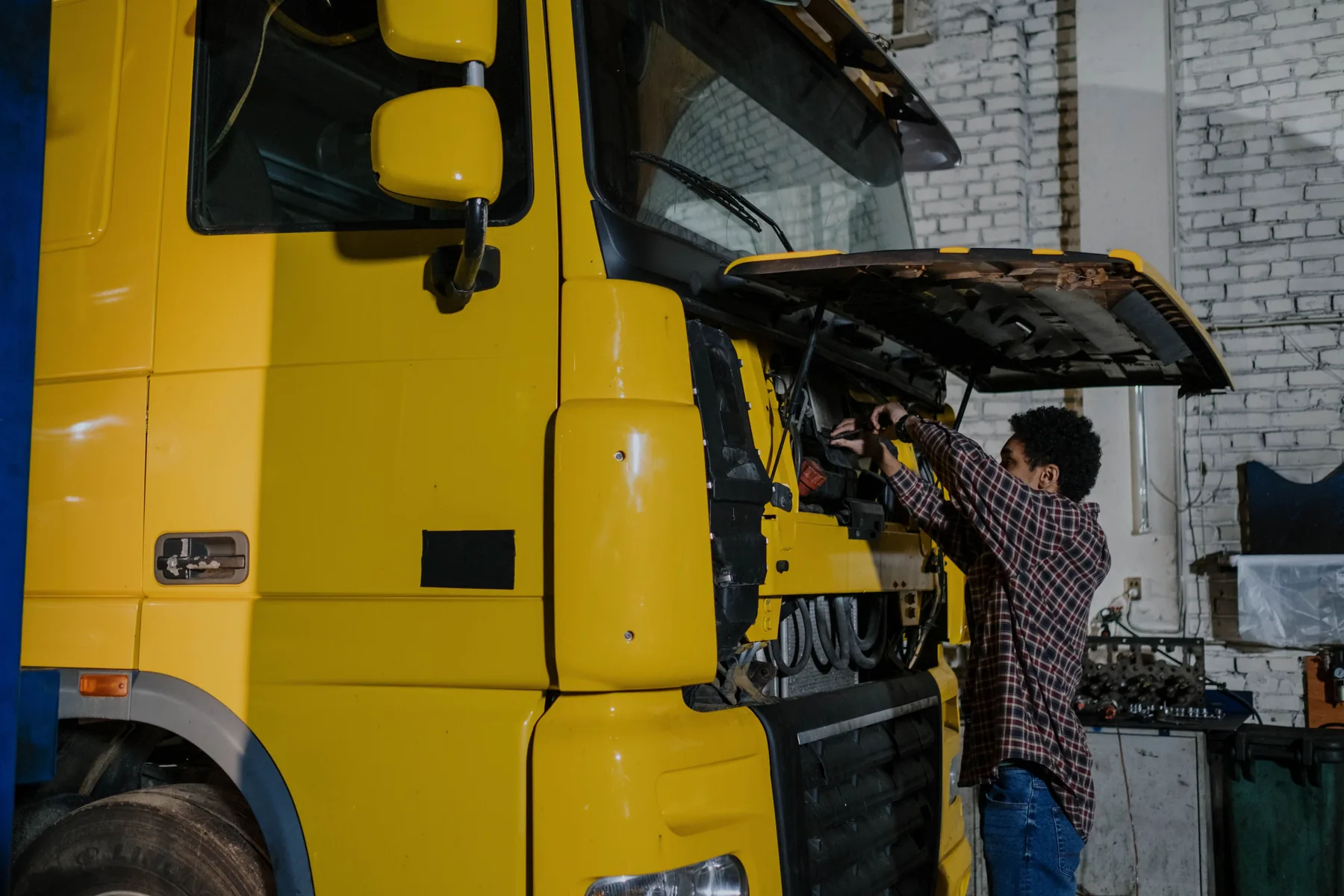 Person arbeitet an einem schweren Nutzfahrzeug in einer Werkstatt